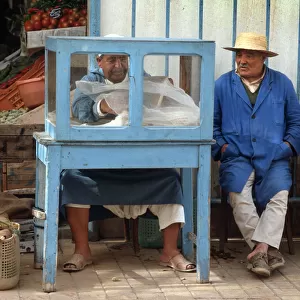 Man sits beside a small food stall in Houmt Souk, Djerba