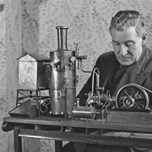 Man working on miniature steam engine