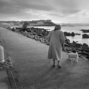 Una signora anziana con un cane bianco a Portstewart, Irlanda del Nord