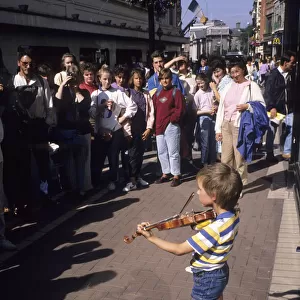 Small boy busking with his violin for an audience in Dublin