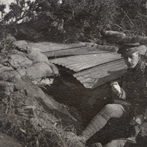 Soldier sitting by a dugout, Northern France, WW1
