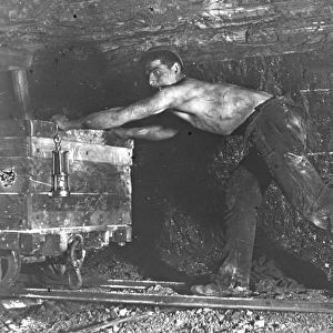 Welsh miner in coal mine pushing truck