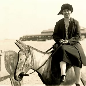 Woman perched on a wooden donkey at the seaside