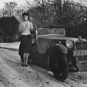 Woman standing by car in snowy weather