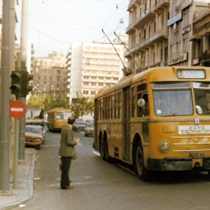 Yellow cable buses on a busy main road in Athens