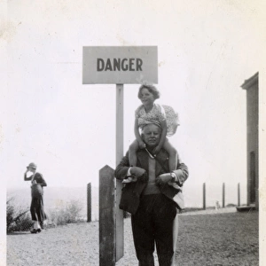 Young girl on Grandfathers shoulders by Danger sign