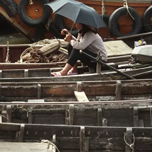 A young woman on a small sampan wooden ferry boat