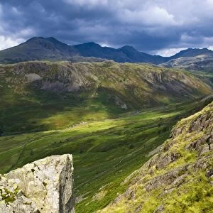 England, Cumbria, Lake District National Park. Looking along the route of the River Esk from the Hardknott Castle Roman Fort, as storms clouds gather above the countrys highest peak, Scafell Pike at 3205ft