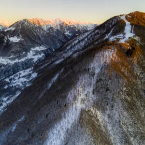 Aerial view by drone of ski slopes of Pian Delle Betulle and Alpe Paglio lit by sunset