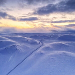 Arctic sunset over Tanafjordveien empty road crossing the snowy mountains after blizzard