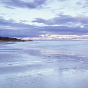 Beach at Alnmouth at dusk with dramatic clouds reflecting in wet sand at low tide