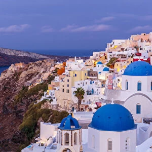 Blue domed white church and colourful buildings at sunrise, Oia, Santorini, Cyclades, Greek Islands, Greece, Europe