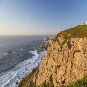 The Cabo da Roca lighthouse overlooks the promontory towards the Atlantic Ocean at sunset