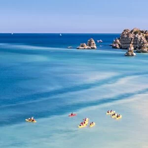 Canoes in the turquoise water of the Atlantic Ocean surrounding Praia Dona Ana beach