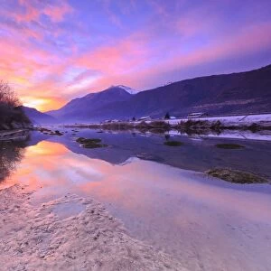 The colors of sunset are reflected in the Adda River, Valtellina, Lombardy, Italy, Europe