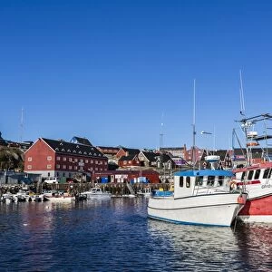 Commercial fishing and whaling boats line the busy inner harbor in the town of Ilulissat, Greenland, Polar Regions