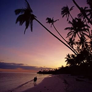 Couple and palm trees on Alona Beach silhouetted at