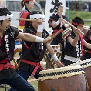 Energetic group of drummers beating Japanese taiko drums during an outdoor performance