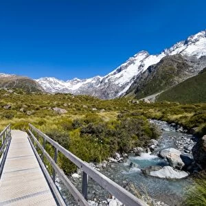 A hiking trail crosses wooden bridge over a creak high up in the mountains, South Island