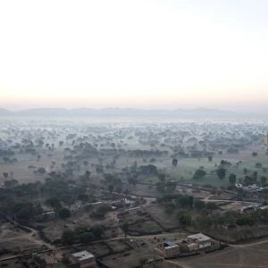 Hot air balloon in the early morning, flying over countryside and the village of Samode