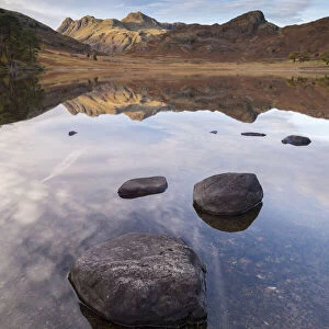 The Langdale Pikes mountains reflected in the mirror still water of Blea Tarn in autumn
