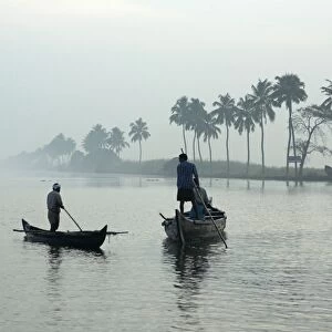 Local villagers paddle shell dredging canoes at sunrise on the backwaters