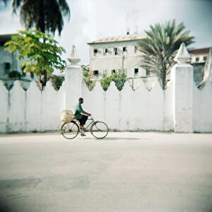 Man on bicycle with old buildings behind, Stone Town, Zanzibar, Tanzania