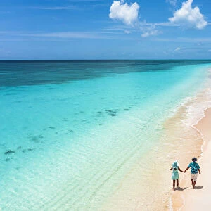 Man and woman walking hand in hand on a beach washed by the turquoise sea, Barbuda, Antigua and Barbuda, West Indies, Caribbean, Central America