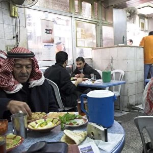 Men in keffiyeh eating traditional humus in Hashem restaurant