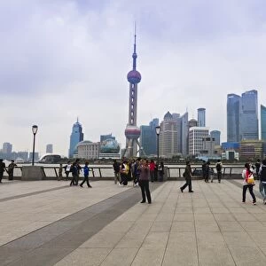 Pedestrians and tourists on the Bund, the futuristic skyline of Pudong across the Huangpu River beyond, Shanghai, China, Asia