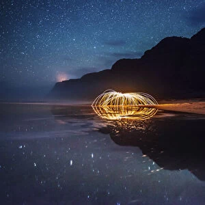 Polihale State Park under a starry sky with sparks being reflected in a tidal pool