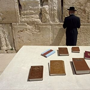 Religious books on table and Jewish man facing the Western Wall