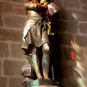 Statue of St. Joan of Arc with coloured light from stained glass, Church of Notre Dame