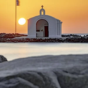 Sun rising over the iconic Agios Nikolaos church and cliffs, Georgioupolis, Crete island, Greek Islands, Greece, Europe