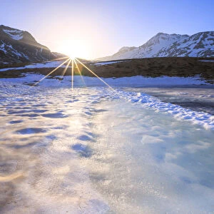 Sunburst on Lake Andossi during thaw, Chiavenna Valley, Spluga Valley, Sondrio province