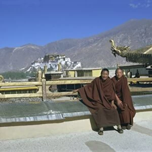 Two Tibetan Buddhist monks at Jokhang temple, with the Potala palace behind