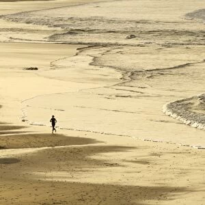 Woman jogging at sunrise on Gwithian Beach, Cornwall, England, United Kingdom, Europe