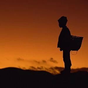 Young boy silhouetted against sky at dusk, Tibet, China, Asia