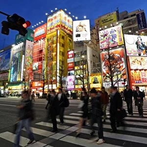 Night scene of people on a zebra crossing and buildings, signs and lights in the street in Akihabara, Electric Town, Tokyo, Japan