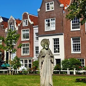 Statue of Jesus Christ and traditional Dutch houses in Begijnhof in Amsterdam, Holland