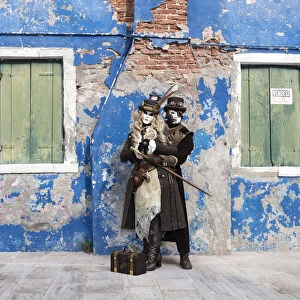 Couple in steampunk costumes in front of old blue house at Carnival time, Burano Island