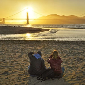 Couple watching sunset at Golden Gate Bridge, Crissy Field, San Francisco, California