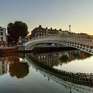 Europe, Dublin, Ireland, Tourists crossing Halfpenny bridge at sunrise