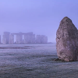 The Heel Stone and Stonehenge at dawn on a misty, frosty morning, Wiltshire, England. Winter (January) 2022