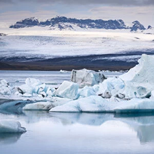 Icebergs floating at Jokulsarlon glacier lagoon against snowcapped mountains, Vatnajokull