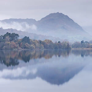 Mist hangs over the lake and island at Grasmere with Helm Crag beyond, Lake District
