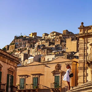 Modica, Sicily. A woman standing on the stairs in front of the baroque Cathedral at