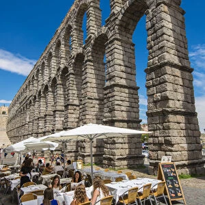 Outdoor restaurant with Roman aqueduct bridge behind, Segovia, Castile and Leon, Spain
