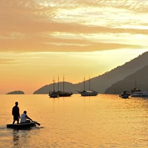 People on dingy paddeling out to ship, cove at Vila do Abrao, Ilha Grande, Rio de Janeiro
