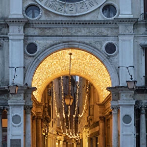 People walk through the illuminated arcade under the clock Tower, St